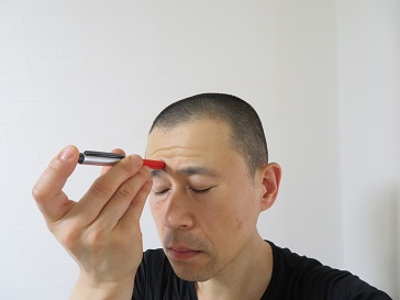 眼精疲労のツボに家庭用電気針　ハリボーイを当てている画像